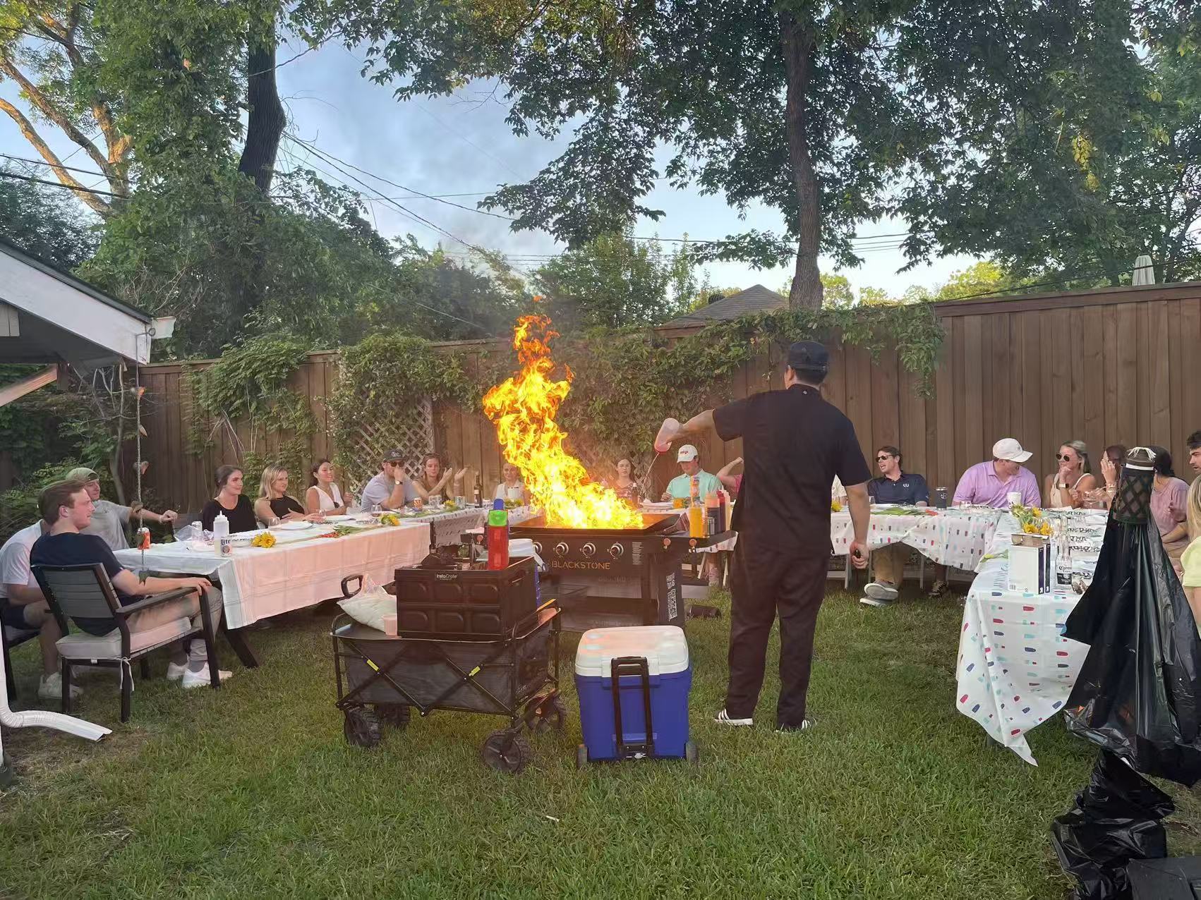 Backyard hibachi fire show with guests around the grill